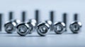 Shiny metal nuts arranged in a line on a reflective surface with a soft focus background symbolizing industrial precision and Royalty Free Stock Photo