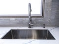 A shiny, metal sink faucet on a beautiful, marble countertop in a high-end kitchen Royalty Free Stock Photo