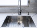 A shiny, metal sink faucet on a beautiful, marble countertop in a high-end kitchen Royalty Free Stock Photo