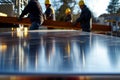 shiny metal table, workers in hard hats carrying lumber outoffocus behind