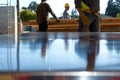 shiny metal table, workers in hard hats carrying lumber outoffocus behind