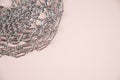 Shiny metalic silver chains on pastel pink surface with copy space