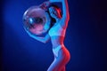 With shiny mirrored ball. Young woman in underwear is in the studio with neon lights