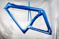 Shiny new fresh fresh paintwork coating paint of a metallic blue carbon racing road bicycle frame set with fork in front of paint Royalty Free Stock Photo