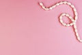 Shiny pearl necklace on a pink background, top view Royalty Free Stock Photo