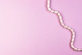 Shiny pearl necklace on a pink background, top view Royalty Free Stock Photo