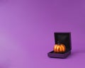 Shiny pumpkin in ring gift box for fun Halloween present concept. Purple and orange scheme Royalty Free Stock Photo