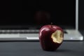 Shiny red apple resting on an open aluminum laptop in selective focus on a black background Royalty Free Stock Photo