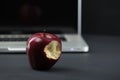 Shiny red apple resting on an open aluminum laptop in selective focus on a black background Royalty Free Stock Photo