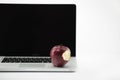 Shiny red apple resting on an open aluminum laptop in selective focus on a black background Royalty Free Stock Photo