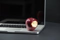 Shiny red apple resting on an open aluminum laptop in selective focus on a black background Royalty Free Stock Photo