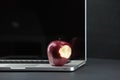 Shiny red apple resting on an open aluminum laptop in selective focus on a black background Royalty Free Stock Photo