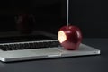 Shiny red apple resting on an open aluminum laptop in selective focus on a black background Royalty Free Stock Photo