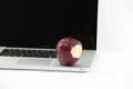 Shiny red apple resting on an open aluminum laptop in selective focus on white background Royalty Free Stock Photo