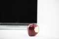 Shiny red apple resting on an open aluminum laptop in selective focus on white background Royalty Free Stock Photo