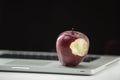Shiny red apple resting on an open aluminum laptop in selective focus on white background Royalty Free Stock Photo