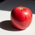A shiny red apple sits on a white surface, casting a distinct shadow Royalty Free Stock Photo