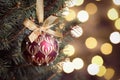 Shiny red ball hanging on Christmas tree against festive lights, closeup. Space for text Royalty Free Stock Photo