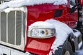 Shiny red big rig semi truck tractor standing for truck driver rest on the winter truck stop parking lot with snow and ice Royalty Free Stock Photo