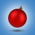 Shiny red Christmas ball in air on blue background Royalty Free Stock Photo