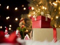 Shiny red gift box and christmas dolls with blurry christmas tree and bokeh lights background Royalty Free Stock Photo