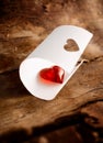 Shiny red heart nestling in curled white paper