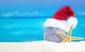 Shiny silver ball in Santa\'s hat with starfish on sand of beach Royalty Free Stock Photo
