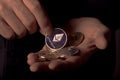 Shiny silver ethereum coin of cryptocurrency in male hand palm over black background, close up. Eth putting into crypto