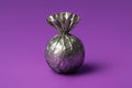 A shiny silver foil wrapped sphere with a tied top on a purple surface Royalty Free Stock Photo