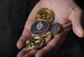 Shiny silver and gold coins of cryptocurrency in male hand palm over black background, close up. Pile of ethereum