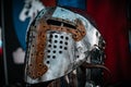 Shiny silver medieval iron knight helmet with a golden cross, full of scratches due to battles