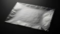 A shiny silver metallic foil packet captured with studio lighting on a dark surface Royalty Free Stock Photo