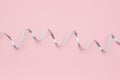 Shiny silver ribbon streamers serpentine on pink background in minimal style. Concept decorations for celebration, party, holiday Royalty Free Stock Photo