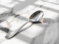 Shiny silver spoon on marble surface sunlight Royalty Free Stock Photo