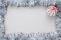 Shiny silver tinsel with a Christmas ball borders a blank white background. Top view