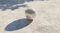 A shiny sphere casts a shadow on a light beige textured surface. Royalty Free Stock Photo