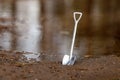 Shiny steel shovel by the pond, water and mud