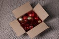 Shiny tinsels and baubles in cardboard box on carpet, above view Royalty Free Stock Photo
