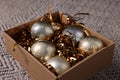 Shiny tinsels and baubles in cardboard box on carpet, closeup Royalty Free Stock Photo