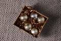 Shiny tinsels and baubles in cardboard box on carpet, top view Royalty Free Stock Photo