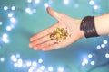 Shiny tiny golden stars in open human palms on a blue background with bokeh.
