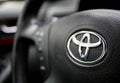 Shiny Toyota logo on steering wheel, shallow depth of field.