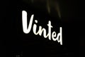 Shiny Vinted logo sign at night. New Vinted office in Vilnius.