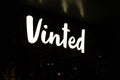 Shiny Vinted logo sign at night.