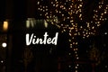 Shiny Vinted logo sign at night.