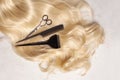 Shiny wavy blonde hair with hair cutting shears and comb on white background, top view Royalty Free Stock Photo