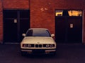 Shiny white car parked in front of a brick building with two large garage doors Royalty Free Stock Photo
