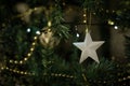 Shiny white star hanging on a decorated christmas tree. Close up Royalty Free Stock Photo