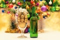 Shiny christmas balls in a beer glass next to a green bottle and a decorated new year tree Royalty Free Stock Photo