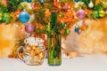 Shiny christmas balls in a beer glass next to a green bottle and a decorated new year tree Royalty Free Stock Photo